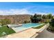 Sparkling pool and spa combination features lush green turf and a natural desert backdrop at 11 Morninglow Pass, Henderson, NV 89052