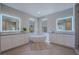 Luxurious bathroom featuring a soaking tub, double vanities with lighted mirrors, and modern fixtures at 11359 Winter Cottage Pl, Las Vegas, NV 89135