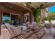 Covered patio with stylish outdoor seating and a glimpse of the dining room through sliding glass doors at 11359 Winter Cottage Pl, Las Vegas, NV 89135