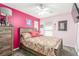Cozy bedroom features light and dark pink walls, a ceiling fan, and natural light from the window at 11739 Village Arbor St, Las Vegas, NV 89183