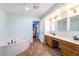 Bathroom features double sinks, wooden cabinets, a soaking tub, and a view into the attached main bedroom at 120 N Phyllis St, Las Vegas, NV 89110