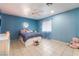 Blue bedroom featuring tile floors, fan, and a large window at 120 N Phyllis St, Las Vegas, NV 89110