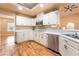The bright kitchen boasts white cabinets, stainless steel appliances, and beautiful wood-look flooring at 120 N Phyllis St, Las Vegas, NV 89110