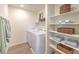 Well-organized laundry room featuring washer, dryer, shelves, and storage baskets at 2633 Begonia Falls Ave # 88, North Las Vegas, NV 89081