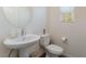 Stylish powder room with a pedestal sink, round mirror, and window at 2691 Mango Light Ave, North Las Vegas, NV 89086