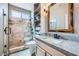 A modern bathroom with a walk-in shower, granite countertops, and a decorative mirror at 2810 Somerset Springs Dr, Henderson, NV 89052
