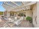 Relaxing outdoor patio area with a pergola, white chairs, and a glass table for entertaining at 2810 Somerset Springs Dr, Henderson, NV 89052