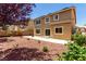 Tan two-story home with backyard featuring rock landscaping, patio, and trees at 432 Emerald Heights St, Las Vegas, NV 89144