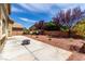 Landscaped backyard with patio, rockscape, block wall, trees, and bright blue sky at 432 Emerald Heights St, Las Vegas, NV 89144