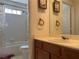 Bathroom with a single sink vanity, framed mirror, and a combined tub and shower with a white tiled surround at 6086 Sunken River Trl, Las Vegas, NV 89118