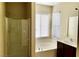 Bathroom with a walk-in shower, soaker tub, dark brown vanity, and a window with blinds at 7563 Captain Lord Ct, Las Vegas, NV 89166