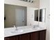 Double sink bathroom with light countertops, dark cabinets, and large mirrors at 7563 Captain Lord Ct, Las Vegas, NV 89166