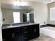 Spacious bathroom vanity with dual sinks, a large mirror, and natural light; tub in the background at 7861 Hamilton Pool Dr, Las Vegas, NV 89113
