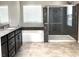 Bathroom featuring dark cabinetry, double sinks, a bathtub, and a walk-in shower with decorative stone accents at 7861 Hamilton Pool Dr, Las Vegas, NV 89113