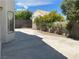 View of the backyard showing the concrete surface and block wall with trees, offering privacy and potential for landscaping at 8432 Apple Hill Ct, Las Vegas, NV 89128