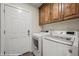 Convenient laundry room with a white washer and dryer and wooden cabinets above at 942 Shadow Hawk Rdg, Mesquite, NV 89027