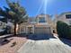 Two-story home featuring a tan exterior, two-car garage, and low maintenance rock landscaping at 10574 Salmon Leap St, Las Vegas, NV 89183