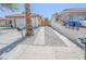 Long driveway leading to a detached garage, with desert landscaping and a wooden gate visible in the background at 134 Saint Albans Dr, Henderson, NV 89015