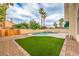 Backyard features artificial grass, patio, tall palm trees, and a pristine pool with a separate spa at 2107 Fountain Springs Dr, Henderson, NV 89074