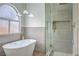 Modern bathroom with a freestanding tub, arched window, and a separate glass-enclosed shower at 2107 Fountain Springs Dr, Henderson, NV 89074