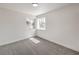 A bright bedroom featuring neutral carpet, two sunlit windows, and fresh white paint at 2107 Fountain Springs Dr, Henderson, NV 89074