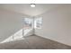 Bright bedroom featuring neutral carpet, base trim, and windows overlooking the neighborhood at 2107 Fountain Springs Dr, Henderson, NV 89074