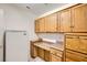 Well-lit laundry room with wooden cabinets, extra counter space and a white refrigerator at 2520 Palmridge Dr, Las Vegas, NV 89134