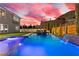 Stunning backyard pool featuring an integrated spa, waterfall feature, and desert landscaping against a vibrant sunset at 2601 Nevada Agave Ln, Las Vegas, NV 89138