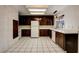 Well-lit kitchen featuring dark cabinetry, white appliances, and tile flooring at 335 Greenbriar Townhouse Way, Las Vegas, NV 89121