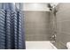 Bathtub and shower combo featuring gray tiling and modern fixtures with a blue shower curtain at 3617 Walnut Wood St, Las Vegas, NV 89129