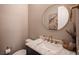 Powder room with marble countertop, modern fixtures, and round mirror at 3698 Regatta Landing Dr, Las Vegas, NV 89141