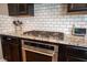 Kitchen with a gas range, stainless steel oven, white subway tile backsplash, and dark cabinets at 3698 Regatta Landing Dr, Las Vegas, NV 89141