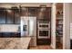 Kitchen featuring stainless steel appliances, dark cabinets, and double ovens next to walk-in pantry at 3698 Regatta Landing Dr, Las Vegas, NV 89141