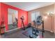 Home gym features a treadmill, mirror, bright red accent wall, and unique colorful lighting at 4110 Bonita Desert Ct, North Las Vegas, NV 89032