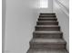 View of a carpeted staircase leading upwards, with white walls, a white handrail, and a small window at the top at 4149 Dignified Ct, North Las Vegas, NV 89032