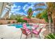 Relaxing pool area with rock features, lush palm trees, and comfortable patio furniture at 5024 Granite Creek Ct, Las Vegas, NV 89131