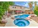 Inviting backyard with a sparkling pool, hot tub, covered patio, and lush landscaping at 5024 Granite Creek Ct, Las Vegas, NV 89131