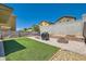 Backyard featuring artificial grass, a BBQ grill, firepit, and block wall, perfect for outdoor living at 6424 Strongbow Dr, Las Vegas, NV 89156