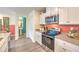 Well-lit kitchen featuring white cabinets, stainless steel appliances, and a view into the half bathroom at 6918 Wrightshire St # 24, Las Vegas, NV 89166