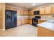 Kitchen features oak cabinets, black appliances, light countertops, and tile flooring at 7491 Speedwell Cavern St, Las Vegas, NV 89139