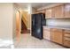Kitchen featuring light wood cabinetry, black refrigerator, and tile flooring near the staircase at 7491 Speedwell Cavern St, Las Vegas, NV 89139