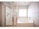 Bright bathroom featuring walk-in shower and an inviting, tiled soaking tub under a window at 7500 Peaceful Brook St, Las Vegas, NV 89131