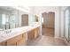 Bathroom with a double sink vanity with cabinets, a walk-in shower, and view to carpeted bedroom at 7500 Peaceful Brook St, Las Vegas, NV 89131