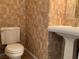 Bathroom showcasing a white pedestal sink, toilet, and textured wallpaper at 7788 Soda Canyon St, Las Vegas, NV 89139