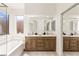 Stylish bathroom with dual sinks, wood cabinetry, and a large tub with shower at 8317 Fritzen Ave, Las Vegas, NV 89131
