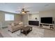 Comfortable living room with a large sectional sofa, ceiling fan, TV, and dark wood accents at 9469 Coral Shine Ct, Las Vegas, NV 89123