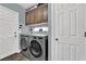 Well-equipped laundry room featuring front load washer and dryer with functional cabinetry above at 10902 Fintry Hills St, Las Vegas, NV 89141