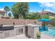 Outdoor kitchen area with a built-in grill, bar seating, and a view of the pool at 10902 Fintry Hills St, Las Vegas, NV 89141