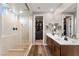Modern bathroom featuring dual sinks, a glass enclosed shower, and access to a walk-in closet at 12430 Foxtail Run Ave, Las Vegas, NV 89138