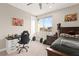 Bedroom with a dark wood bed frame, desk, ceiling fan and a large window offering neighborhood views at 12430 Foxtail Run Ave, Las Vegas, NV 89138